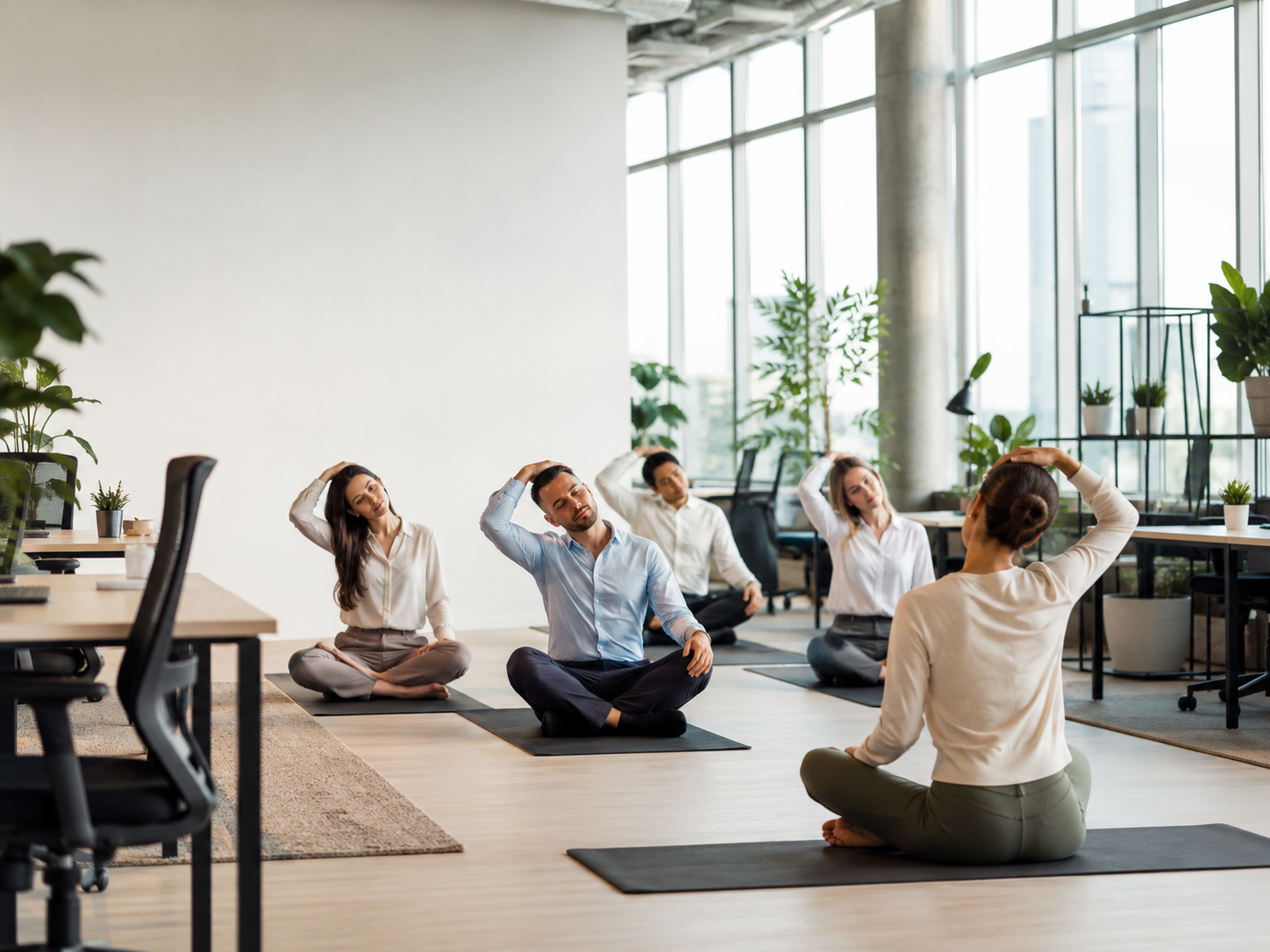 Employees doing office yoga stretches in a bright modern workplace